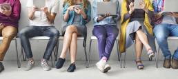 persone sedute con in mano uno strumento di connessione: Gestione social network - Creativi Digitali agenzia di comunicazione digital