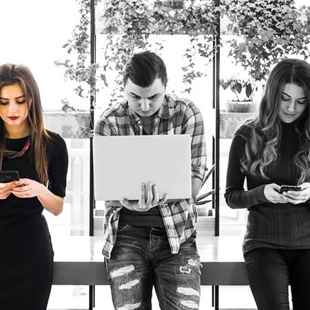 Social Media Trend 2018: nell'immagine persone intente a guardare smartphone, tablet e pc portatile