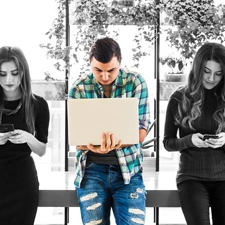 Social Media Trend 2018: nell'immagine persone intente a guardare smartphone, tablet e pc portatile