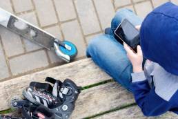 YouTube Kids, app di video per bambini con contenuti sicuri e verificati: nell'immagine un bambino guarda uno smartphone con accanto un paio di rollerblade ed un monopattino