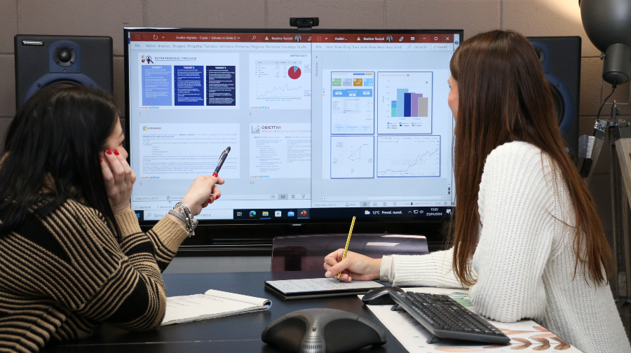 Servizi-digital-marketing 1 Concept per presentazione di servizi di digital marketing: due colleghe analizzano dati.